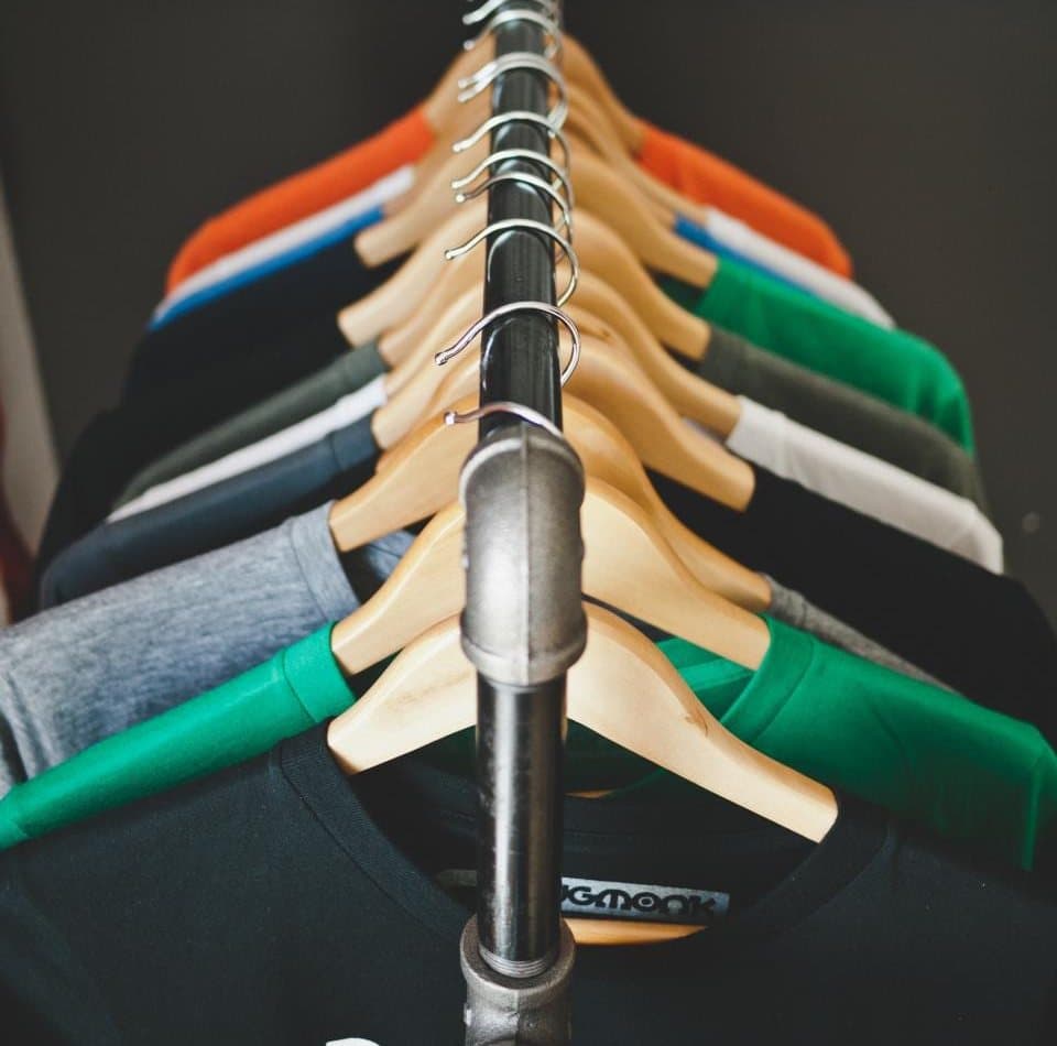 T-shirts de couleur alignés sur des cintres en bois